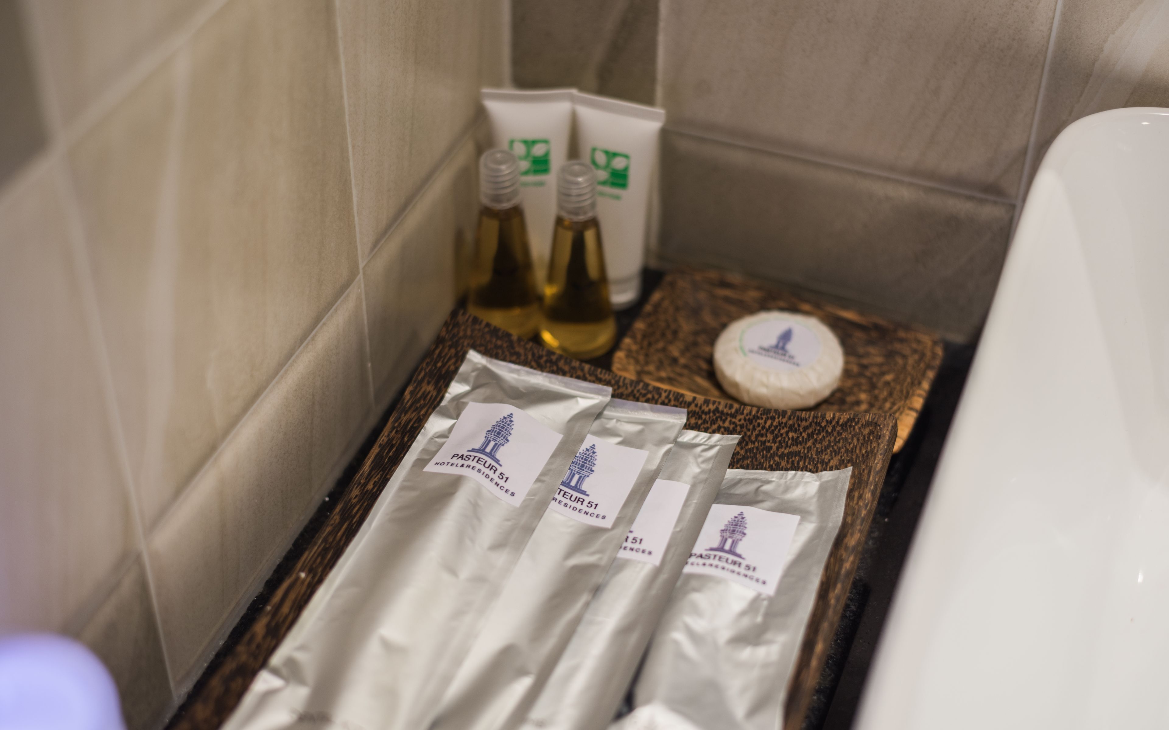 A bathroom with a towel, bottles of lotion, and a bar of soap on a wooden tray.