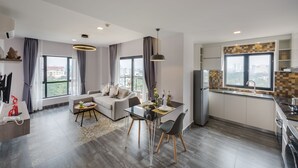 A modern apartment with a living area, dining space, and kitchen. It features large windows, a balcony, and a city view. - Phnom Penh 51 Hotel & Residences (Phnom Penh)