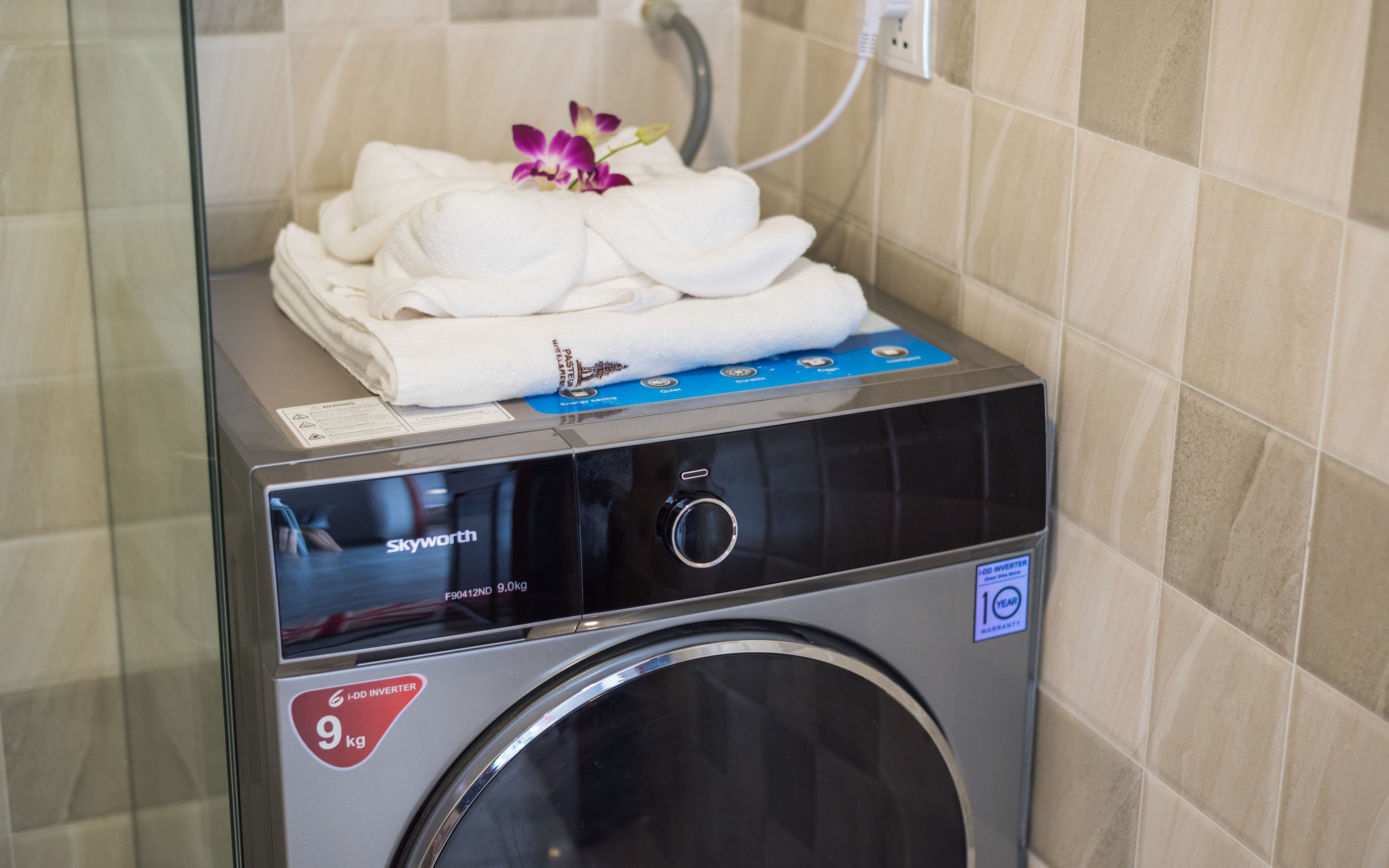 A hotel laundry machine with a 9 kg capacity, a 1-year warranty, and a control panel with various settings.