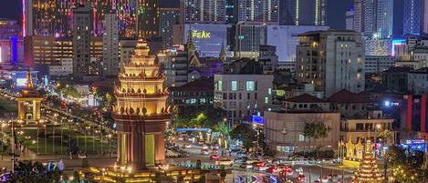 A cityscape with illuminated buildings, a prominent tower, and a busy intersection.