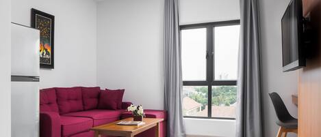 A modern living room with a red sofa, a wooden coffee table, and a TV mounted on the wall.