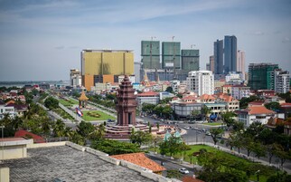 Un paisaje urbano con un monumento destacado al frente, rodeado de edificios modernos y un parque bien cuidado.