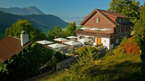 A mountain-view hotel with outdoor seating and a stone wall. - Bürgenstock Hotels & Resort – Taverne 1879 (Ennetbuergen)