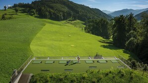 A tennis court surrounded by lush green hills and a forested mountain backdrop. - Bürgenstock Hotels & Resort – Taverne 1879 (Ennetbuergen)