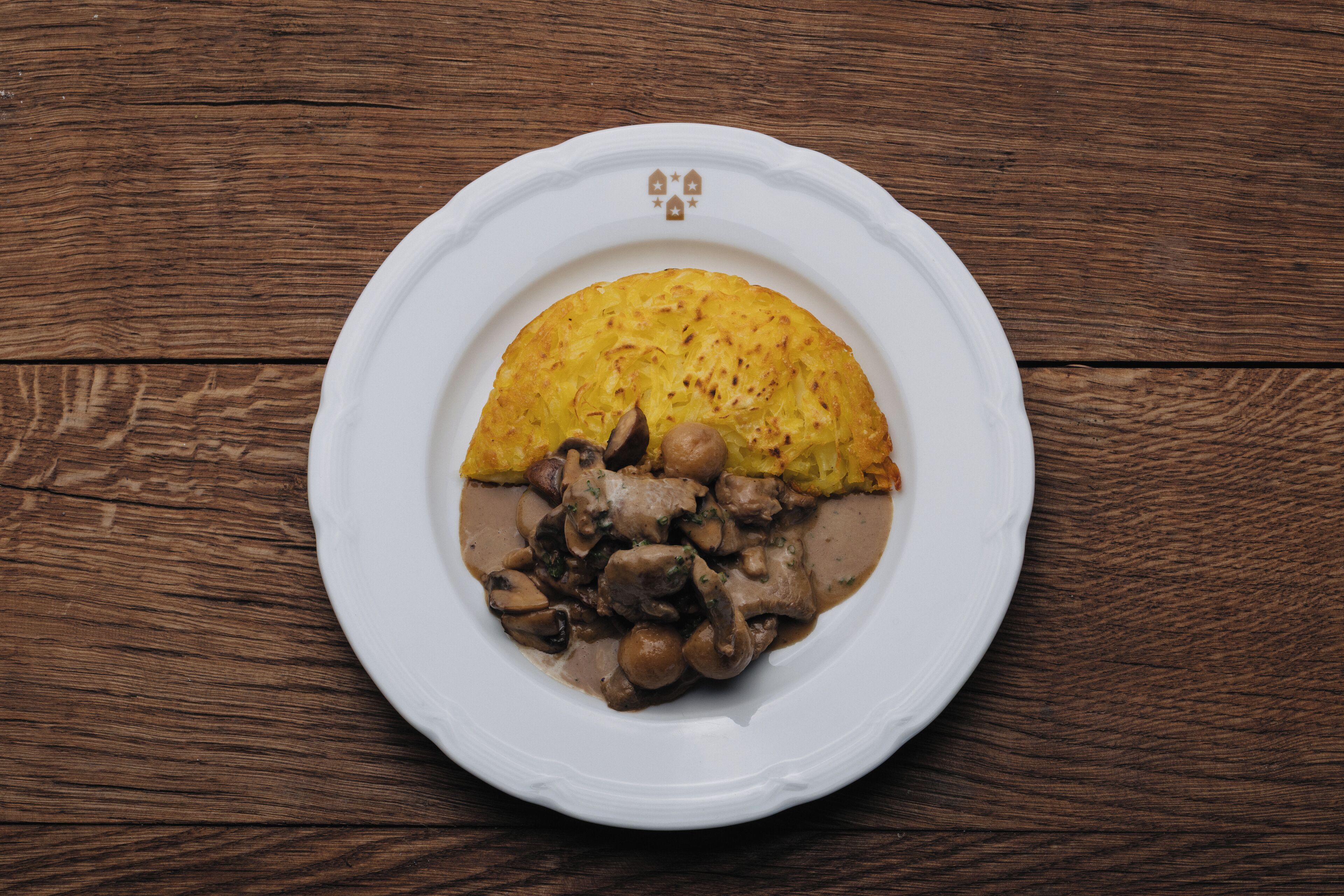 Un plato con una porción de pastel y un guiso de champiñones sobre una mesa de madera.