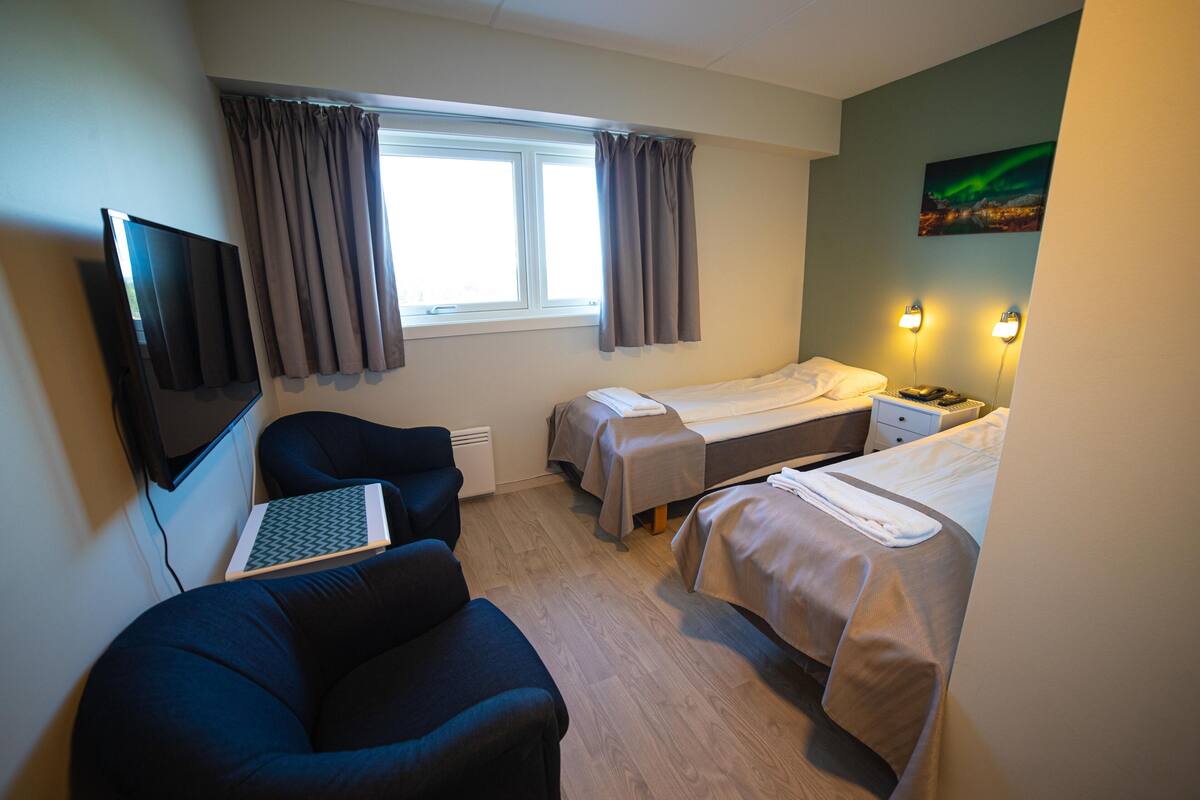 Une chambre d’hôtel avec deux lits, un bureau avec un ordinateur portable, une chaise et une télévision.