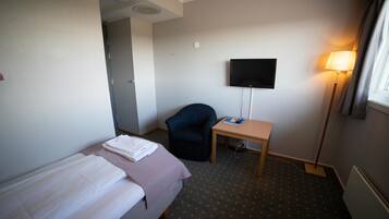 Een hotelkamer met een bed, een bureau, een stoel, een televisie en een lamp.