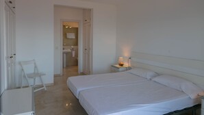 A bedroom with a large bed, a bedside table with a lamp, a chair, and a door leading to a bathroom. - 3 bedroom apartment in Aiguafreda, Begur. Terrace, panoramic views, pool. (Ref:H23) (Begur)