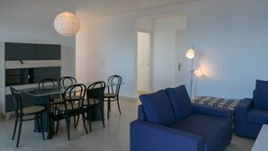 A modern living room with a glass dining table, black chairs, a blue sofa, and a pendant light. - 3 bedroom apartment in Aiguafreda, Begur. Terrace, panoramic views, pool. (Ref:H23) (Begur)