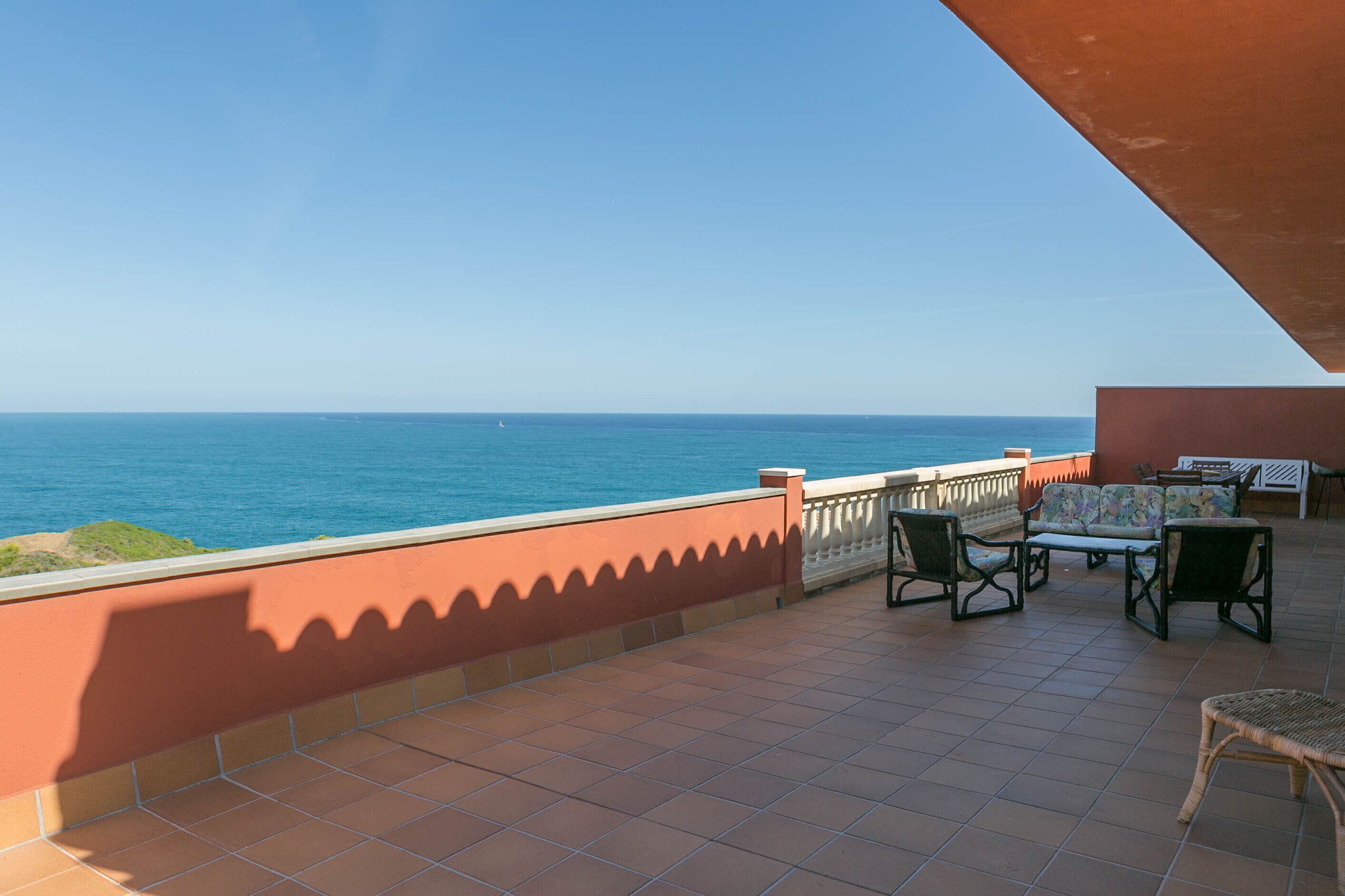 A terrace with a view of the sea, featuring outdoor furniture and a tiled floor.