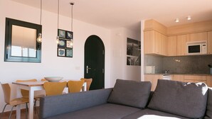 Een moderne woonkamer met een grijze bank, gele stoelen, een witte tafel en een zwarte deur.