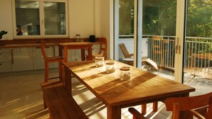 Een houten eettafel met stoelen, een keuken met kasten, en een schuifdeur naar een terras.