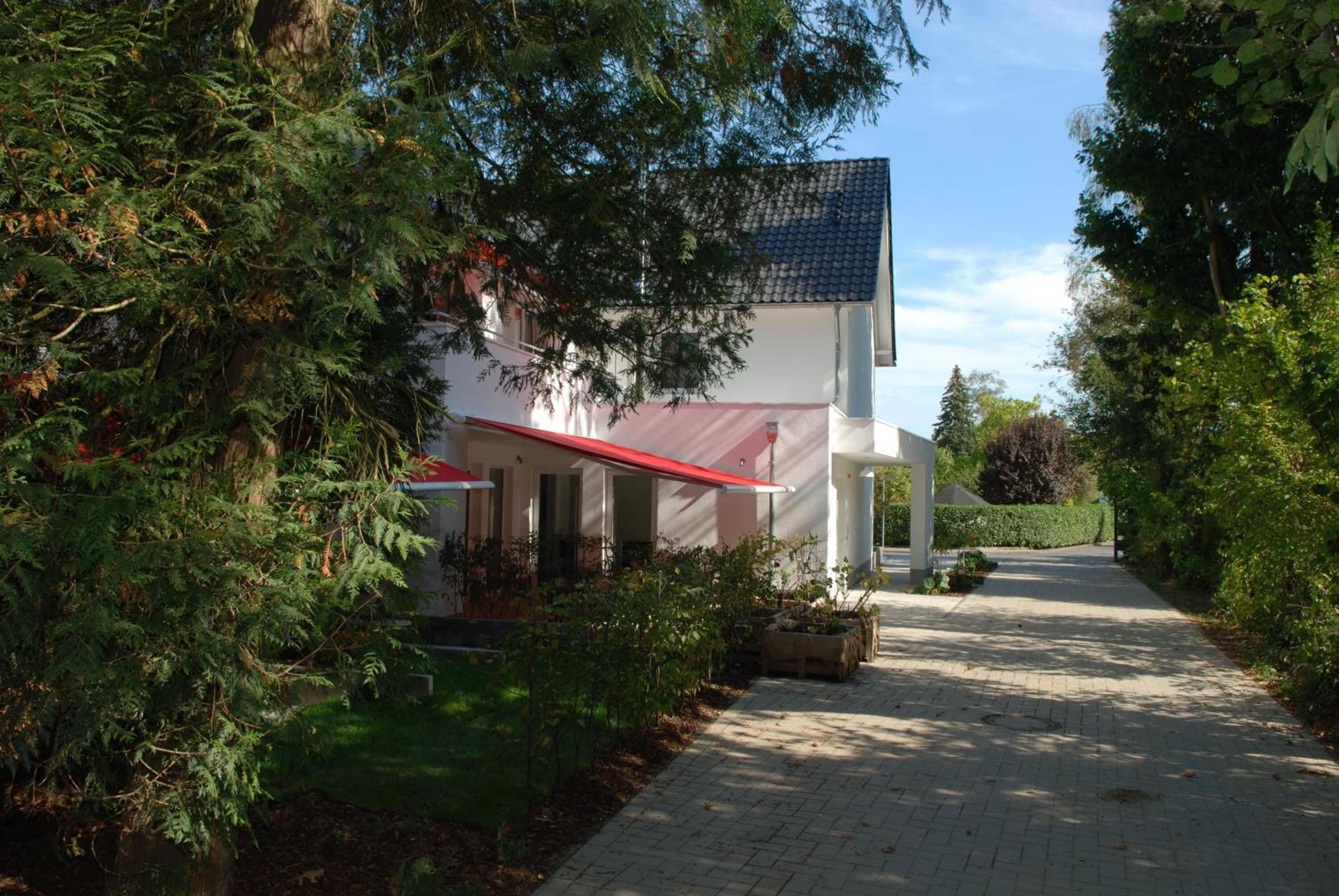Un bâtiment avec un toit rouge et des murs blancs, entouré de verdure.