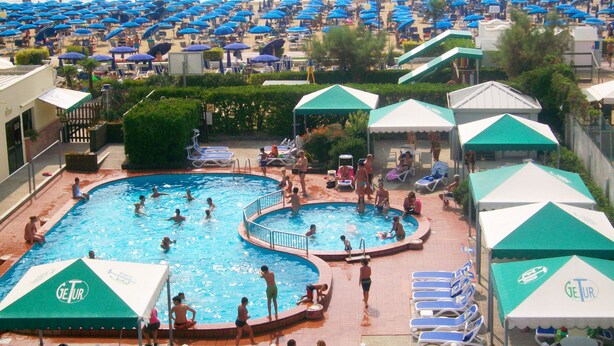 Ein Poolbereich mit mehreren Pools, Liegestühlen und Sonnenschirmen.