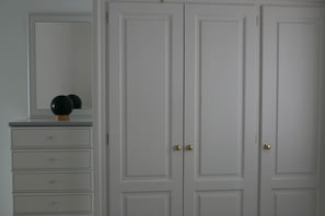 A room with a dresser, mirror, and two doors.