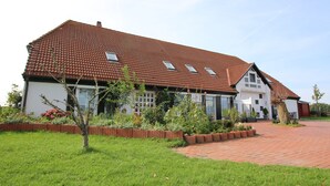 Ein zweistöckiges Haus mit rotem Ziegeldach, einem Ziegelweg und einem gepflegten Garten.
