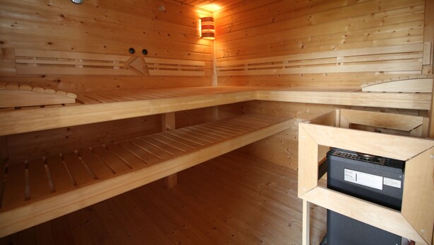 Eine Holzsauna mit Bänken und einer Heizung.