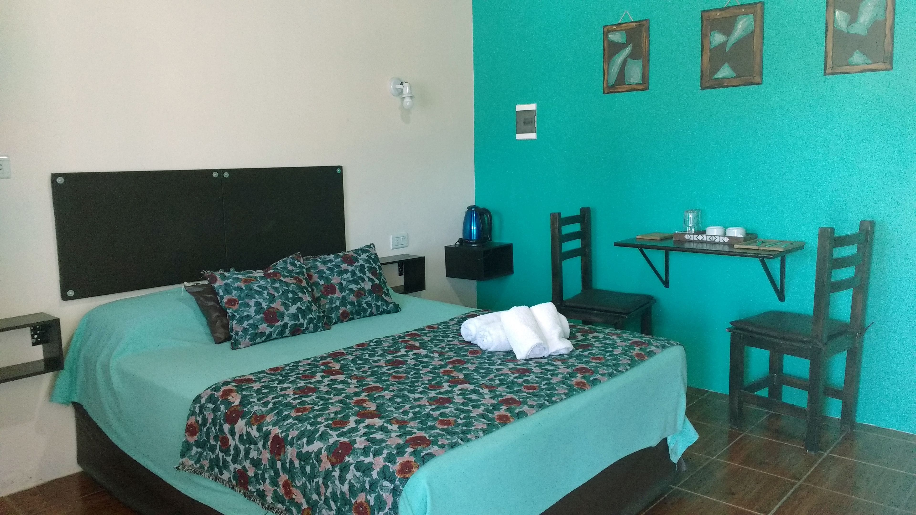 A room with a bed, a small table, and a chair.