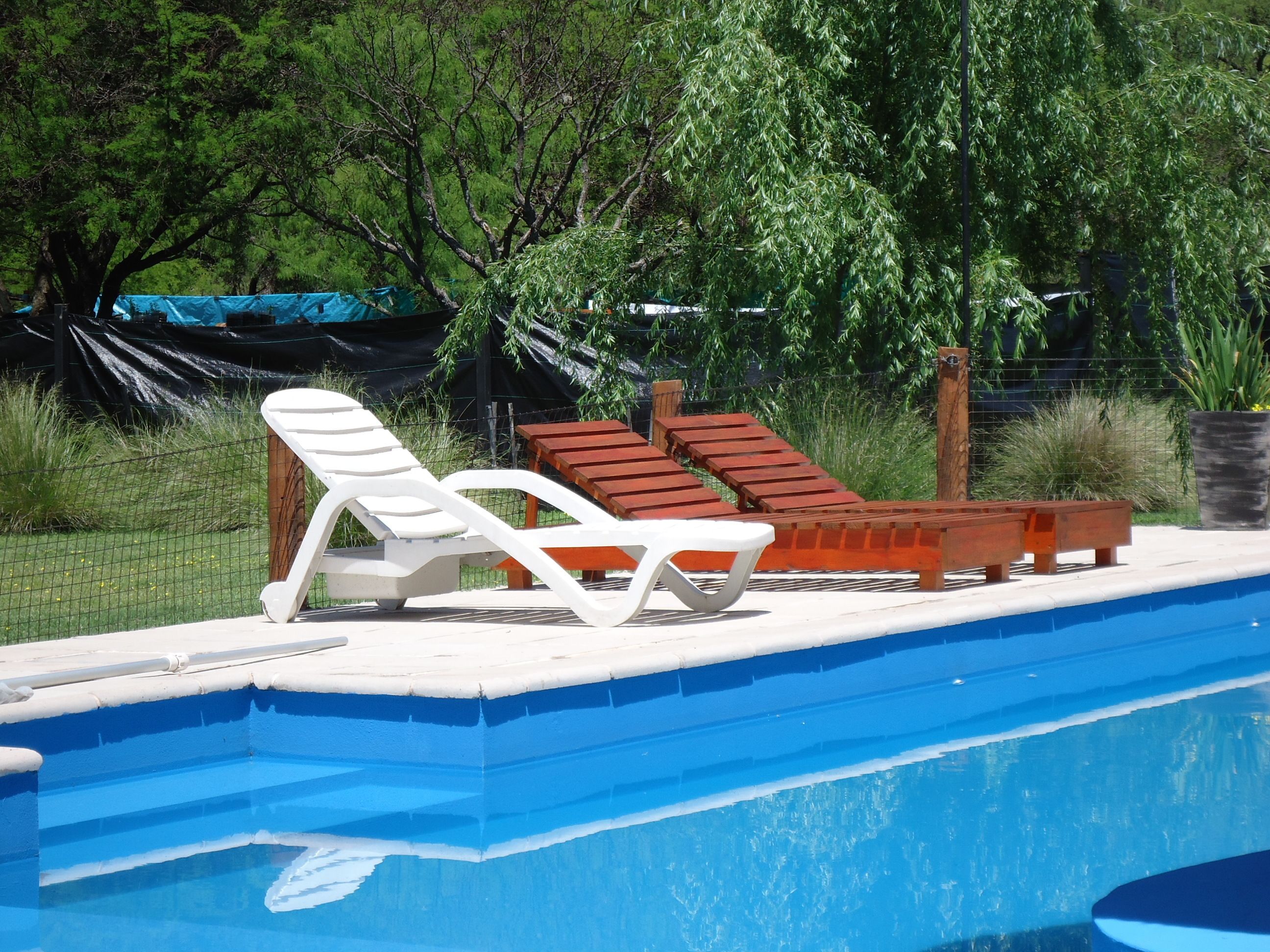 Una piscina con sillones de descanso y una terraza de madera.
