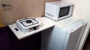 Una kitchenette compacta con estufa a gas, microondas y refrigerador.