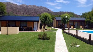 Un complexe hôtelier comprenant deux chalets, une piscine et offrant une vue sur les montagnes.