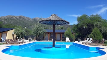 Una piscina al aire libre de temporada, sillones reclinables de piscina