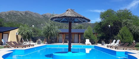 Una piscina al aire libre de temporada, sillones reclinables de piscina