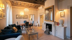 A living room with a fireplace, a chandelier, and a dining area with chairs and a table. - Prestigious apartment with panoramic terrace, located in the center of Cortona. (Cortona)