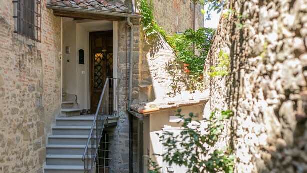 A narrow street with a stone building, a wooden door, and a staircase leading to an upper level. - Prestigious apartment with panoramic terrace, located in the center of Cortona. (Cortona)