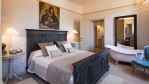 A bedroom with a large bed, a sitting area with a chair, a bathtub, and a mirror. - Prestigious apartment with panoramic terrace, located in the center of Cortona. (Cortona)