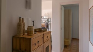 A wooden dresser with decorative items, a wall-mounted light, and a hallway leading to another room. - 2 bedroom apartment in Begur center. Sea views, terrace and pool (Ref:H09) (Begur)