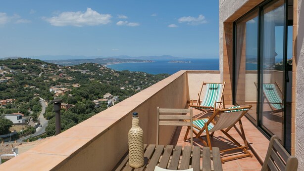 A balcony with a view of the sea, two wooden chairs, and a bottle. - 2 bedroom apartment in Begur center. Sea views, terrace and pool (Ref:H09) (Begur)