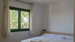 A hotel room with a bed, a window with curtains, a nightstand, and a wall-mounted lamp. - 2 bedroom apartment in Begur center. Sea views, terrace and pool (Ref:H09) (Begur)