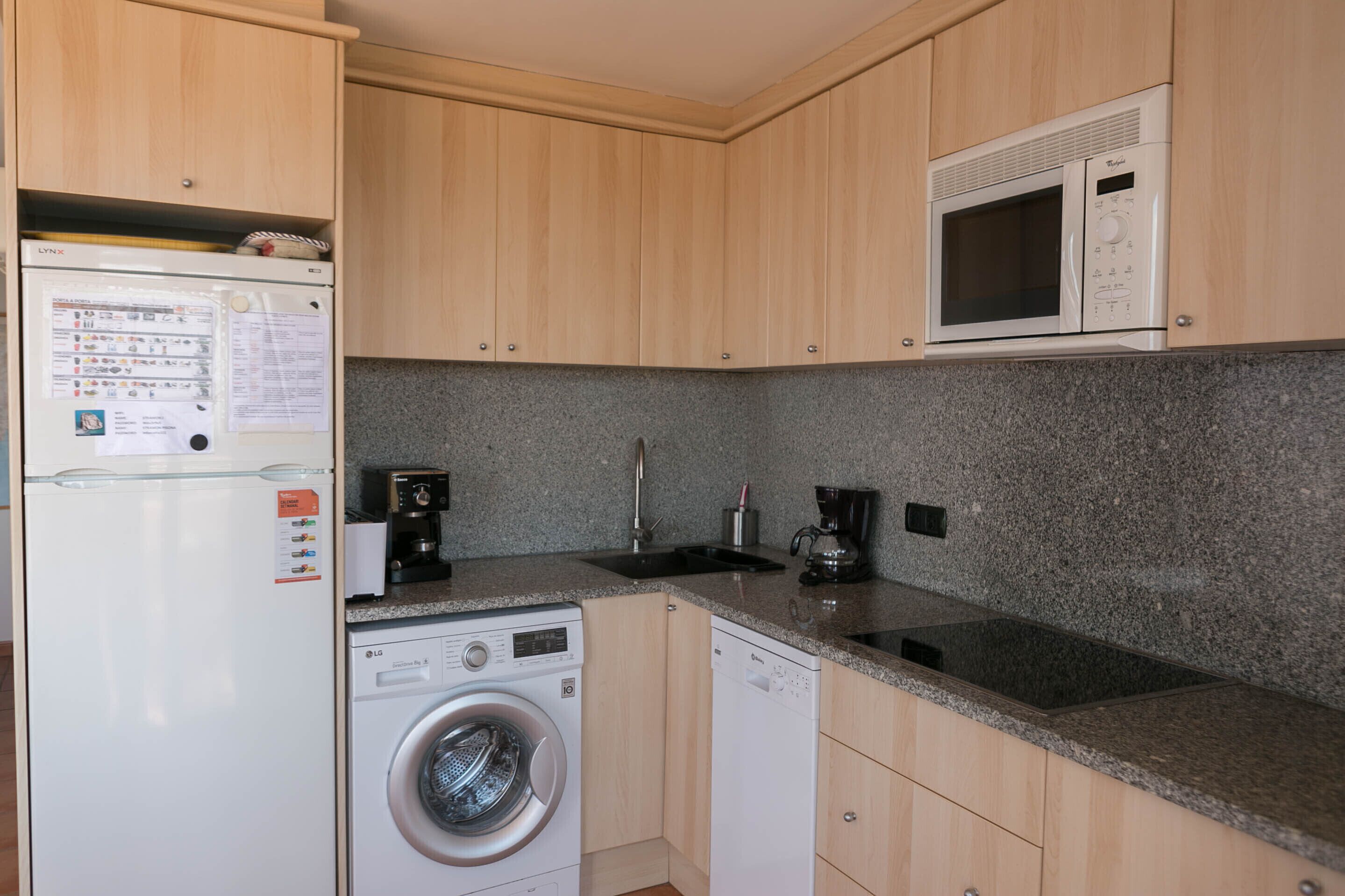 A compact kitchen with a washing machine, a microwave, and a coffee maker.