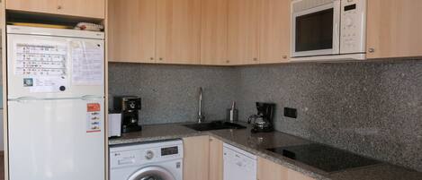 A compact kitchen with a washing machine, a microwave, and a coffee maker.