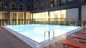 A modern hotel with a rooftop pool, multiple balconies, and a well-lit interior. - Coordinat Suits (Izmir)