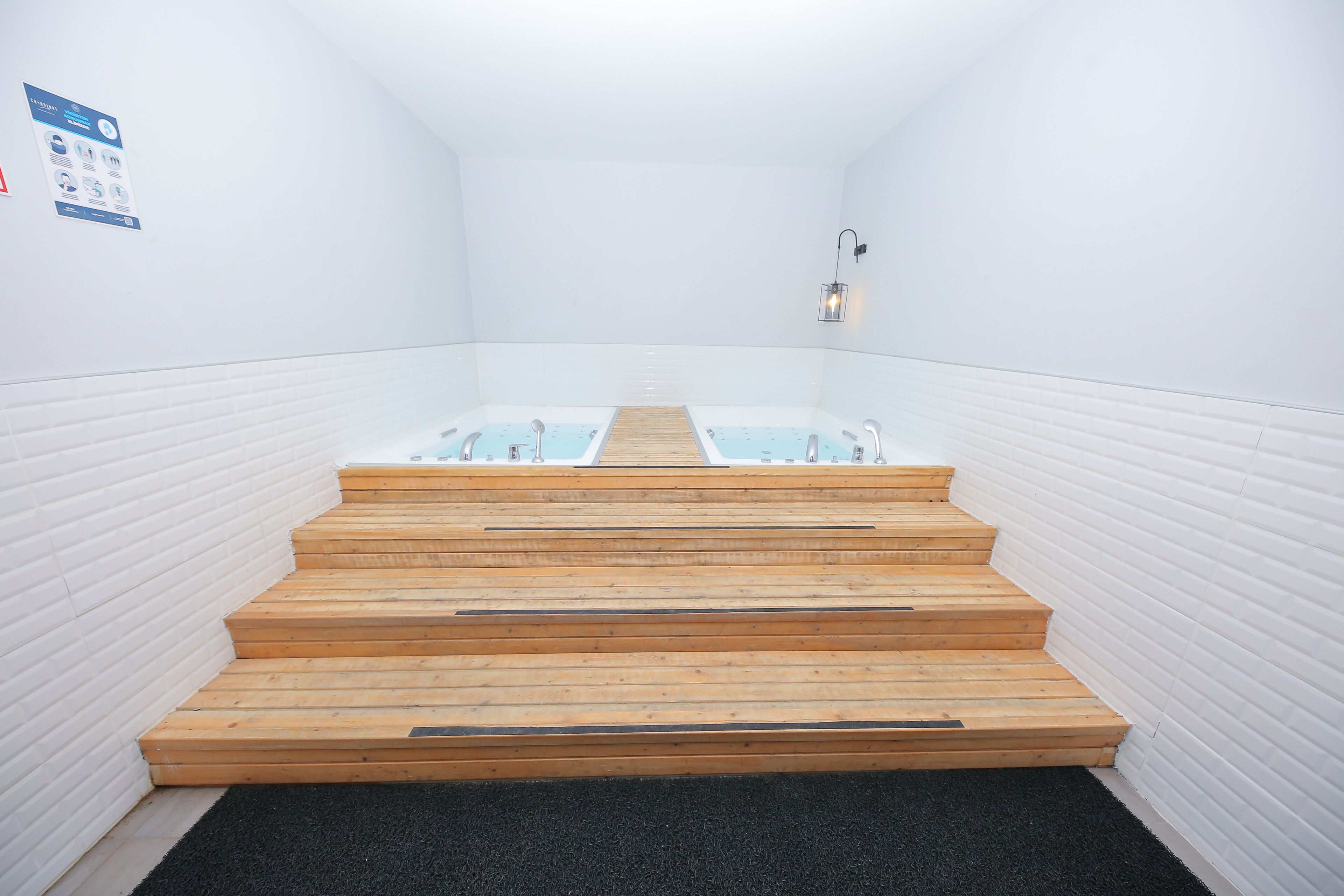 A modern bathroom with two wooden steps leading to a white bathtub.
