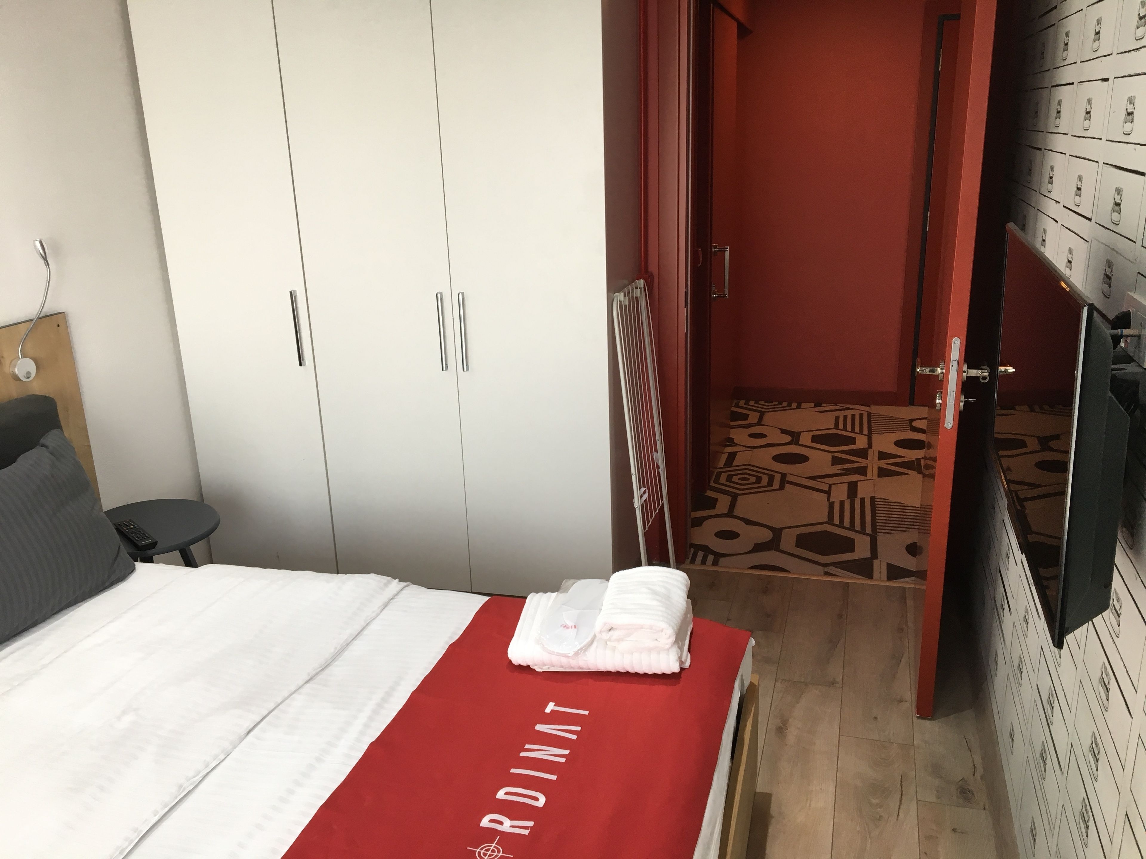 A hotel room with a bed, a wardrobe, a small table, and a television.