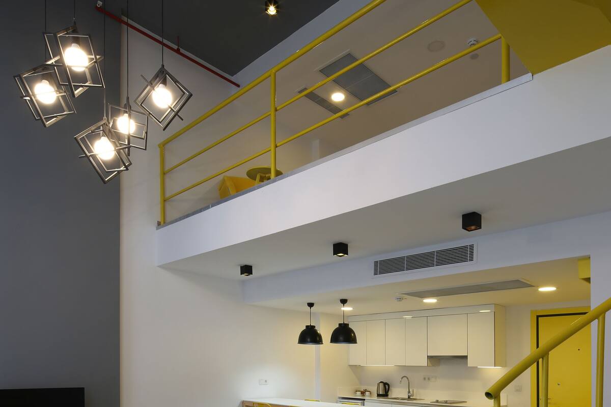 A modern interior with a sofa, dining table, chairs, kitchen, and a staircase.