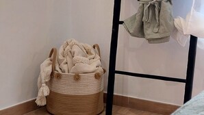 A corner of a room with a woven basket containing a blanket, a bed with a green bedspread, and a black metal ladder leaning against the wall. - independent villa, air-conditioned, ideal for couples (peschici)