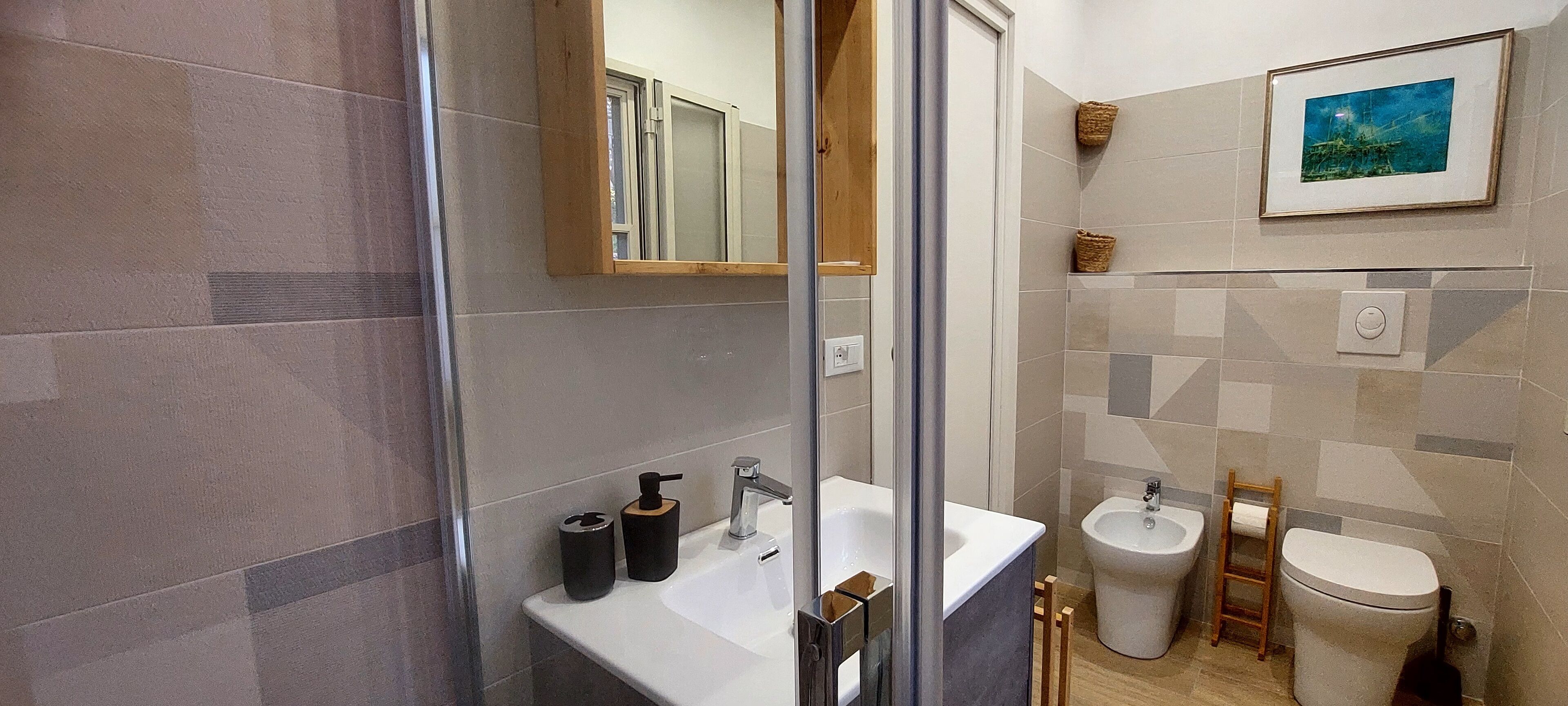 Une salle de bain moderne dotée d’une douche à parois de verre, d’un lavabo avec des articles de toilette, d’un bidet et de toilettes.
