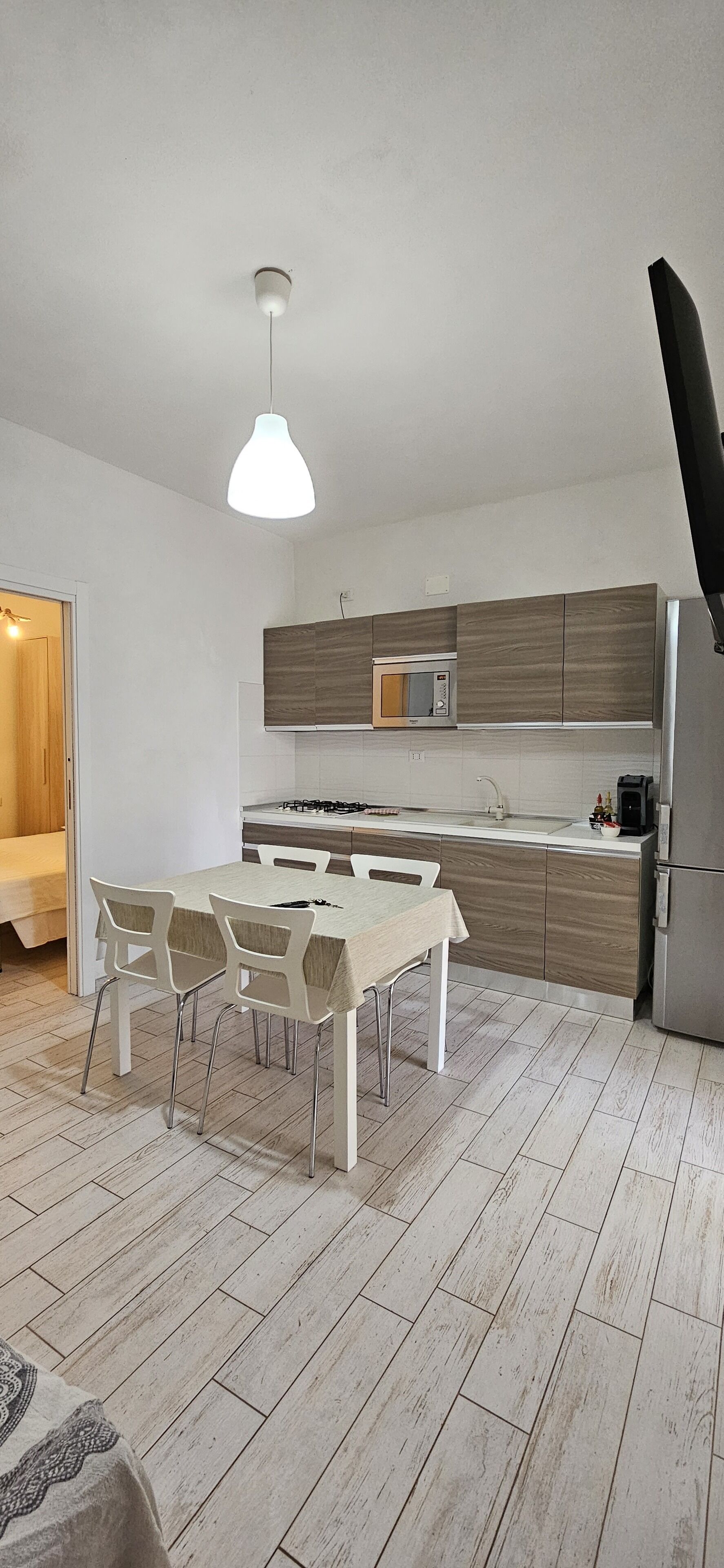 Una cocina moderna con una mesa de comedor, sillas y una lámpara colgante.