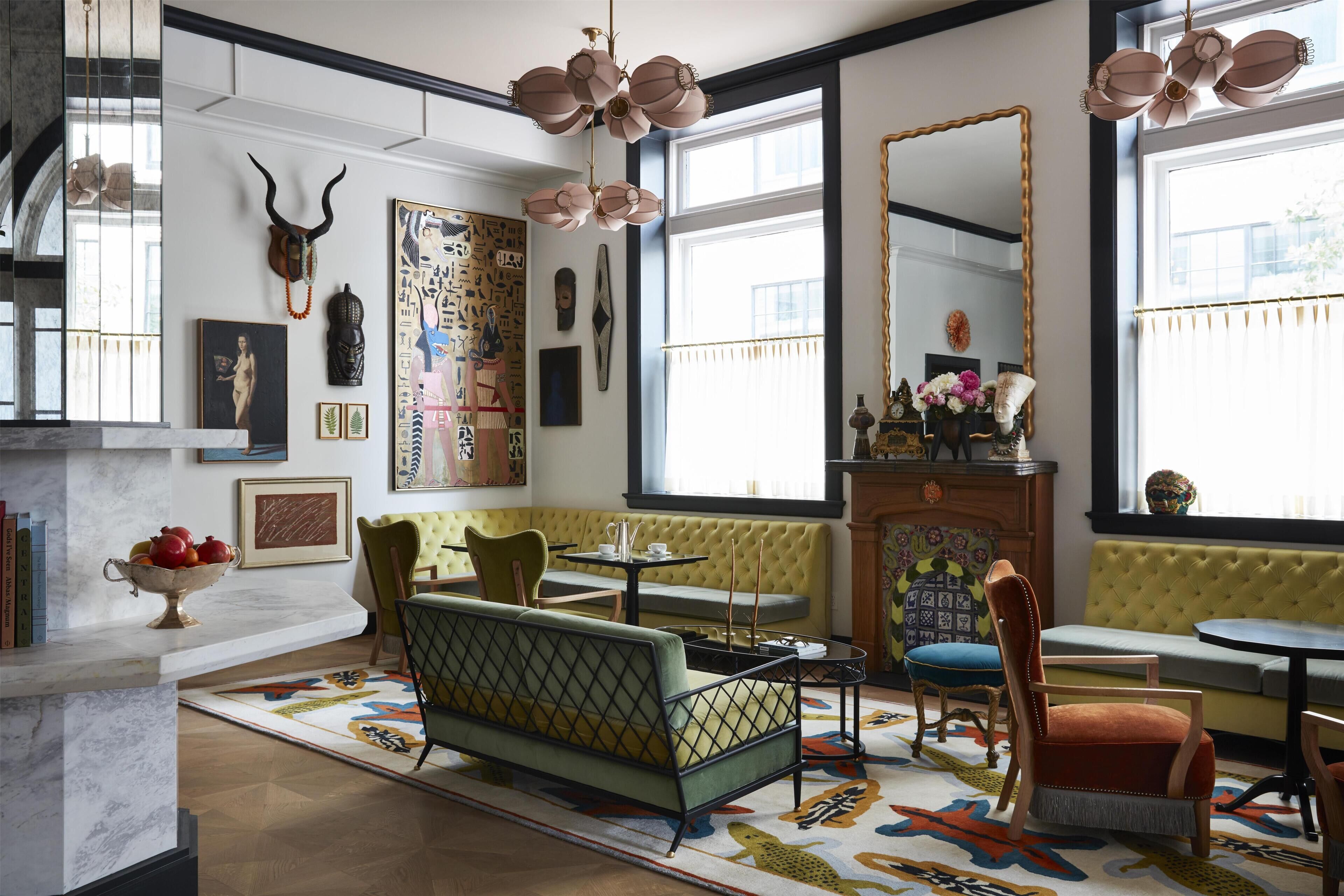 A room with a sofa, chairs, a table, a fireplace, and various wall decorations.