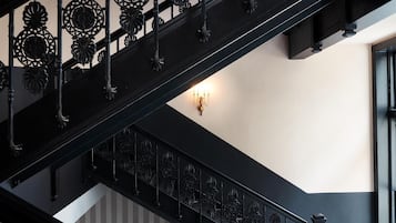 A black metal staircase with ornate railings and a wall-mounted light fixture.