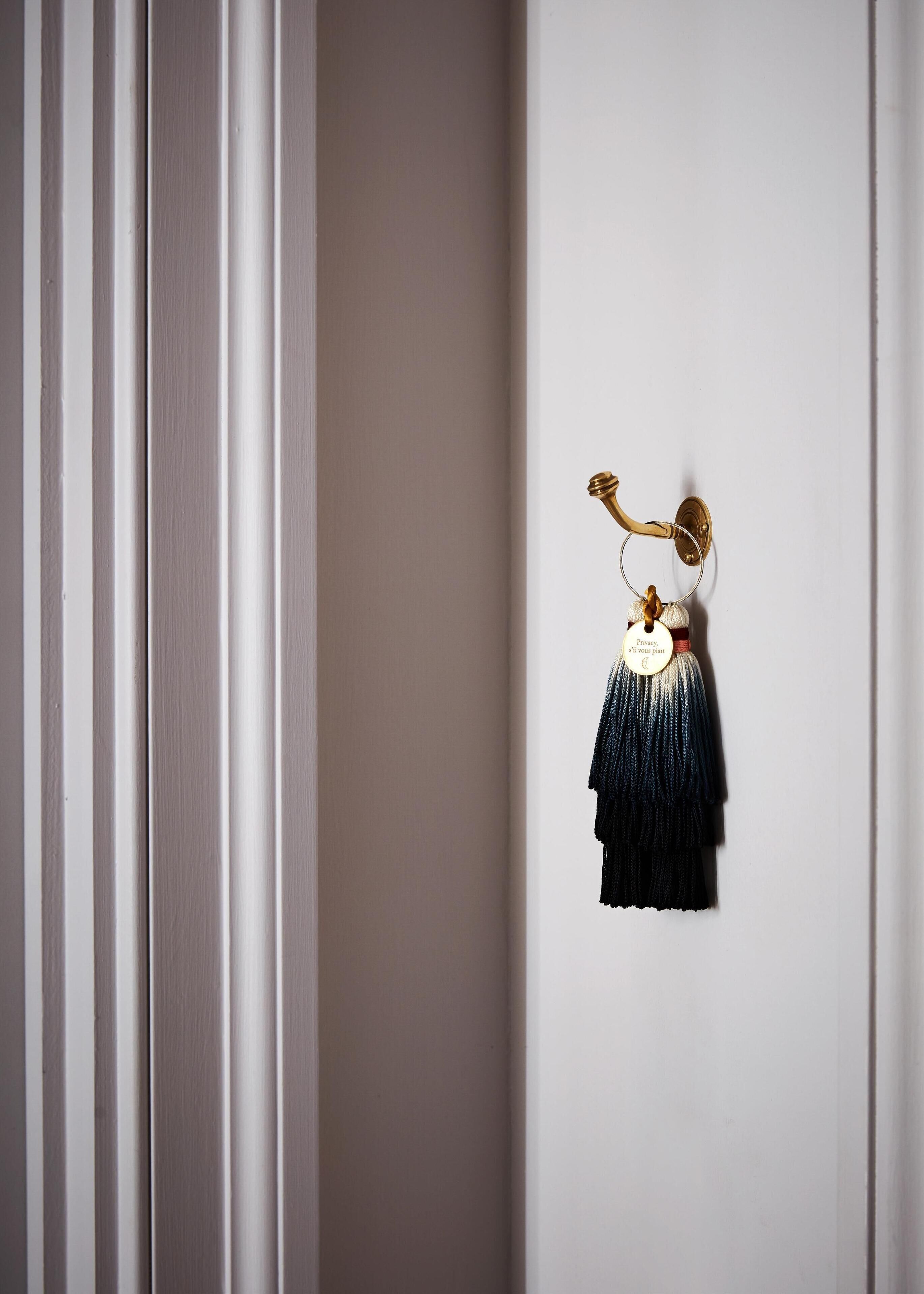 A wall-mounted hook with a tassel and a tag.