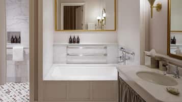 A bathroom with a bathtub, a vanity with a sink, and a large mirror.