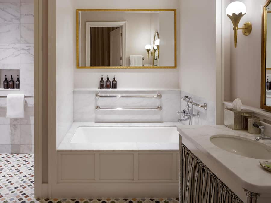 A bathroom with a bathtub, a vanity with a sink, and a large mirror.
