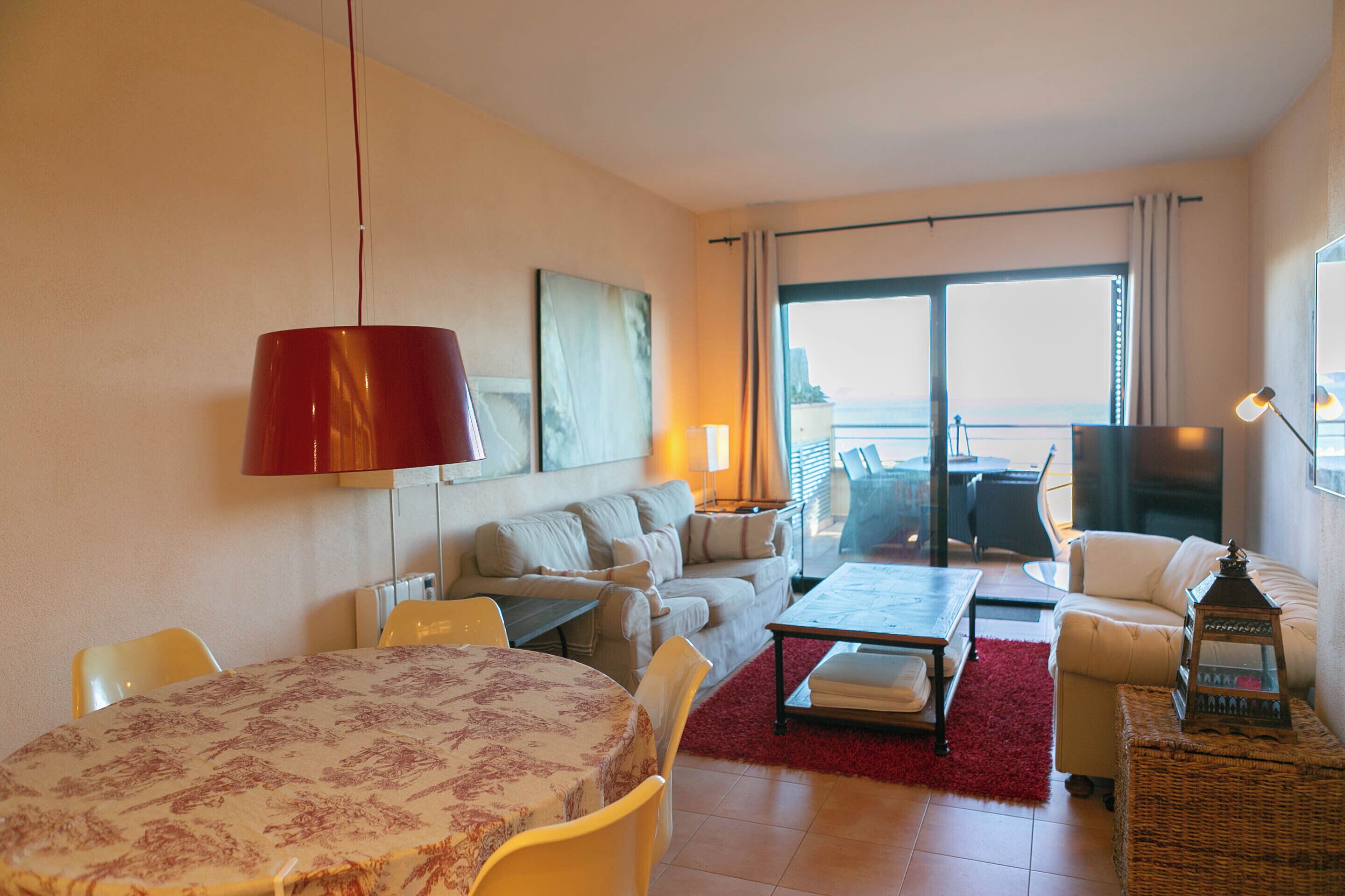A living room with a dining table, sofa, and a large window with a view.