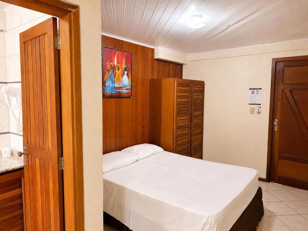 Ein Hotelzimmer mit einem Bett, einem Holzschrank und einem Bild an der Wand.