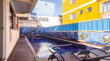 Una piscina al aire libre, sillones reclinables de piscina
